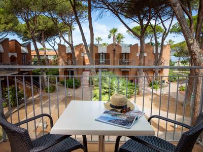 Uitzicht vanaf een balkon met tafel en twee stoelen op een tuin en appartementen.