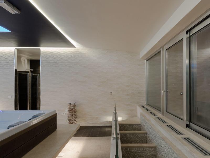 Moderne binnenzwembad met trap en grote ramen, subtiele plafondverlichting.