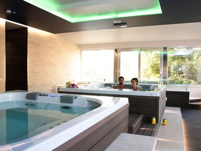 Moderne wellnessruimte met twee hot tubs in een lichte, elegante kamer met grote ramen.