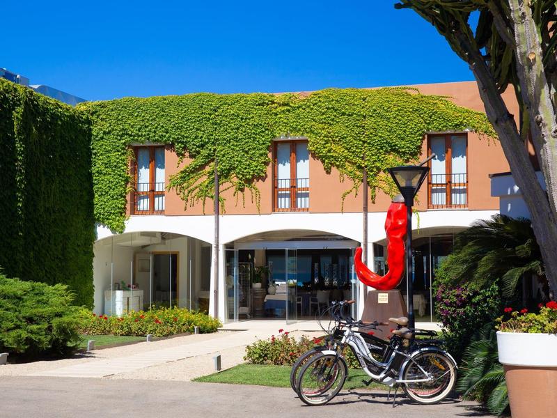 Hotel met groen gevel dak, binnenplaats en geparkeerde fietsen onder een heldere hemel.