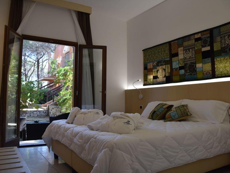 Gezellige hotelkamer met open raam naar een groene tuin.