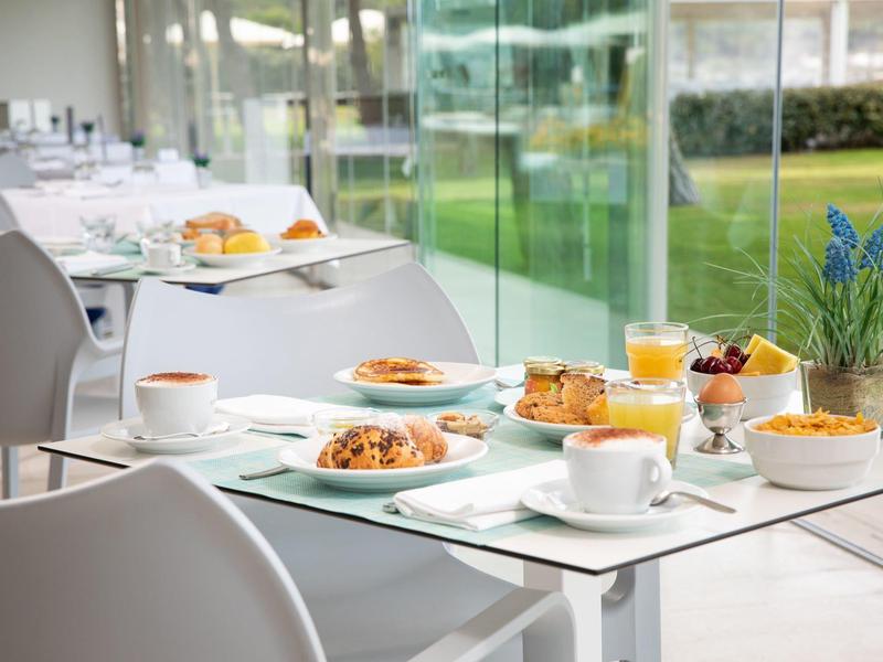 Ontbijttafel met koffie, gebak en muesli in een modern restaurant met glazen wanden.