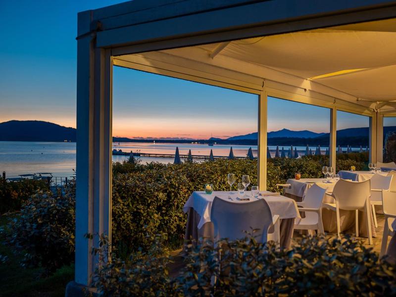 Avondterras met tafels en stoelen met uitzicht op zee en verre bergen.