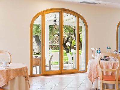 Gezellige eetzaal met houten boogramen en uitzicht op de tuin.