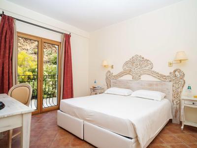 Camera luminosa con letto in legno decorato e balcone con vista sul verde.