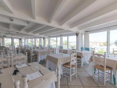 Bright, spacious dining room with set tables and large windows overlooking the sea.