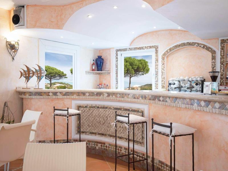Bright bar area with built-in counter, modern seating, and windows overlooking greenery.