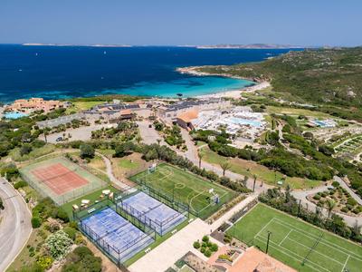 Vista de un resort con campos de tenis y fútbol en la costa con buen tiempo.