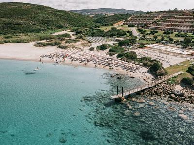 Zona de piscina moderna con tumbonas y camas redondas bajo un cielo azul.