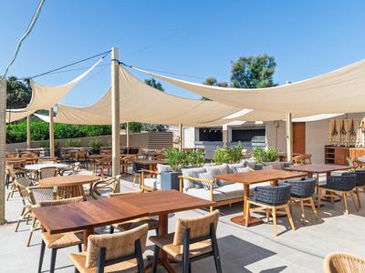 Zona exterior de hotel con mesas, sillas y velas solares bajo un cielo despejado.
