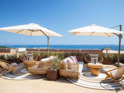 Muebles de salón acogedores con sombrillas y vista al mar en una terraza.