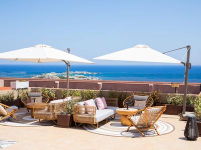 Terrasse avec sièges confortables sous parasols blancs avec vue sur la mer.