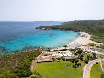 Hôtel côtier avec vue sur une eau turquoise claire et une végétation verte environnante.