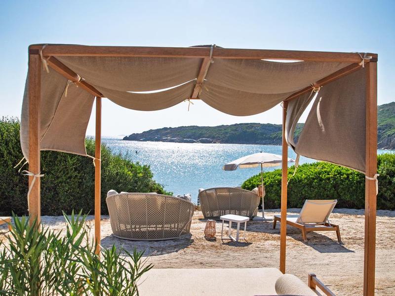 Offene Lounge mit Vorhängen und Meerblick an einem sonnigen Tag.