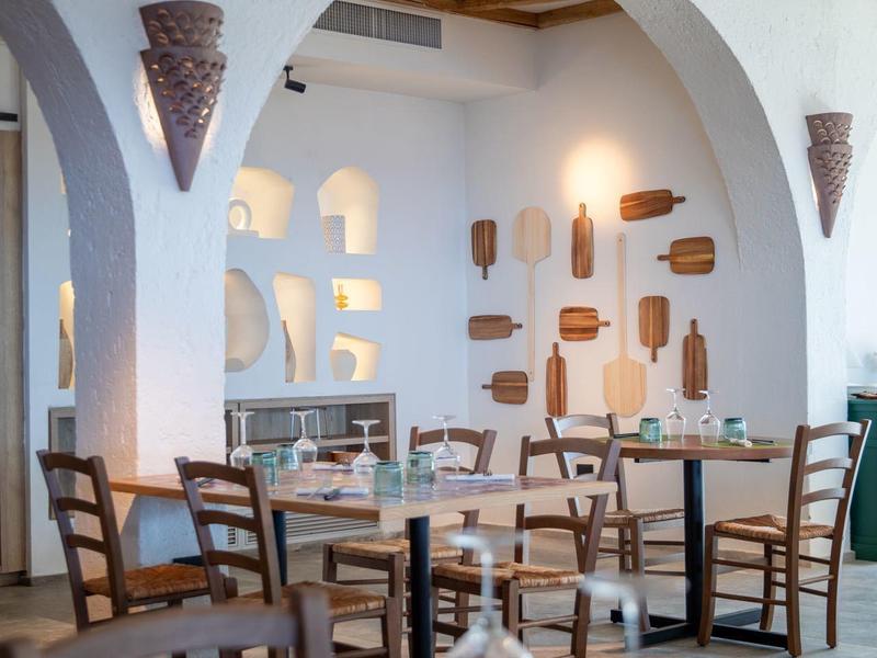 Innenraum eines hellen Restaurants mit Holztischen und Stühlen unter gewölbten Decken.