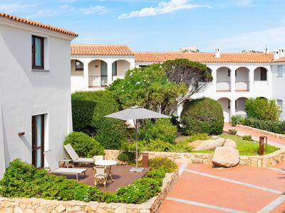 Hotelové nádvoří se zelenými rostlinami, posezením a bíle omítnutými budovami s červenými taškami.