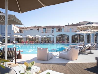 Přátelská oblast u bazénu s deštníky, lehátky a moderním posezením před hotelem.