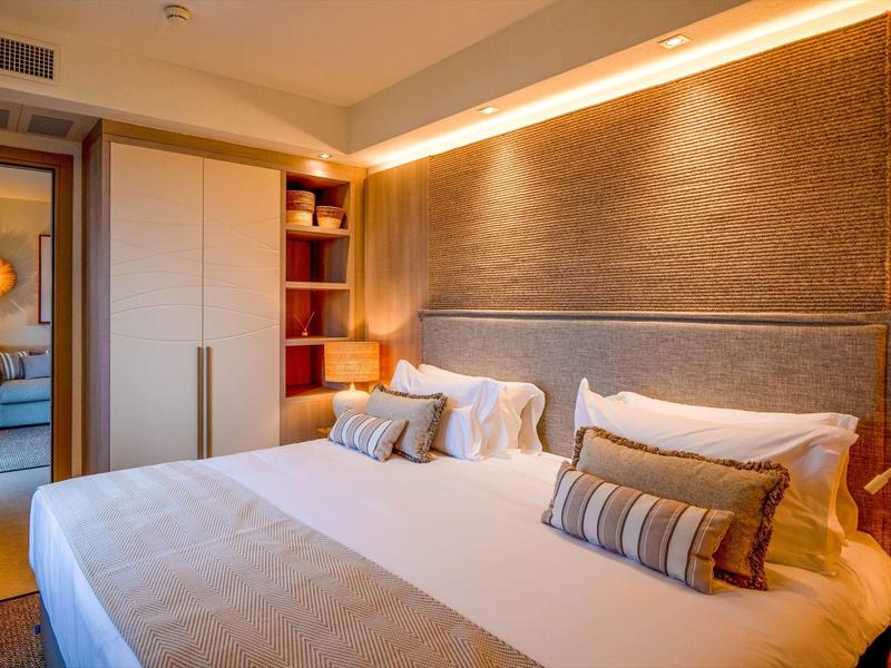 Pohodlný hotelový pokoj s velkou postelí, měkkými polštáři a teplým osvětlením.