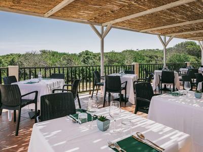 Terrazza sul tetto con tavoli apparecchiati e vista su paesaggio verde sotto cielo sereno.