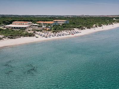 Klares türkisfarbenes Wasser, langer Sandstrand mit Sonnenschirmen und grüner Küstenvegetation.