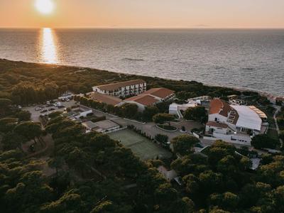 Luchtfoto van een hotel aan de kust bij zonsondergang met de zee op de achtergrond.