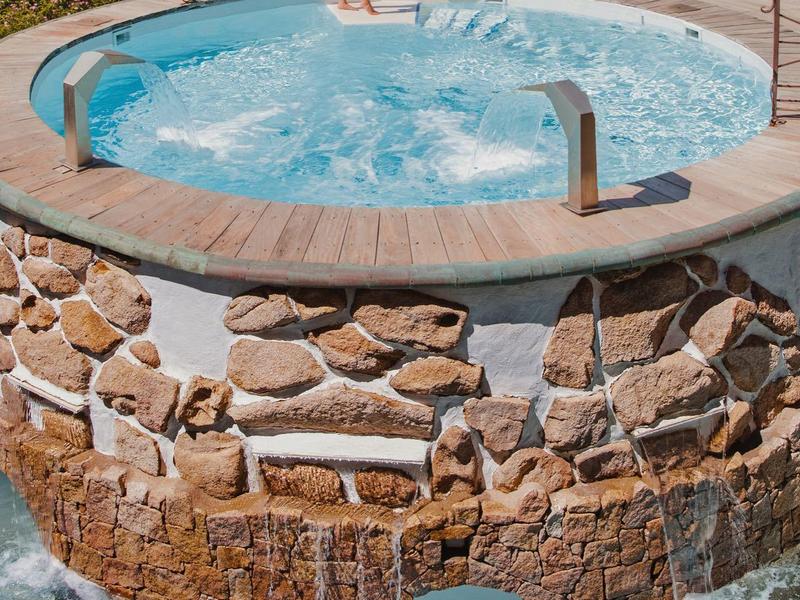 Ronde stenen hot tub met bruisend water en een persoon die erin staat.