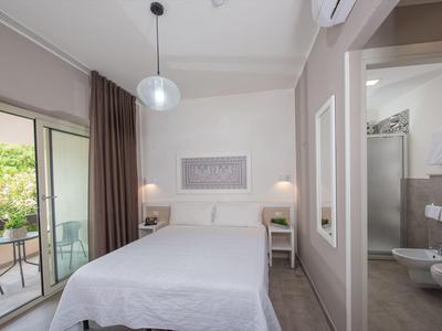 Chambre d'hôtel moderne avec lit double, balcon et salle de bain privée aux tons neutres.
