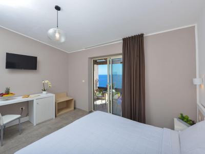 Chambre d'hôtel moderne avec lit double, bureau, télévision et balcon avec vue sur la mer.