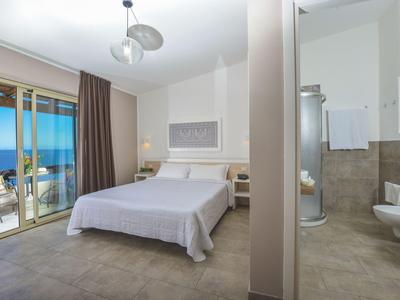 Chambre d'hôtel moderne avec lit double, vue sur la mer et salle de bains attenante.