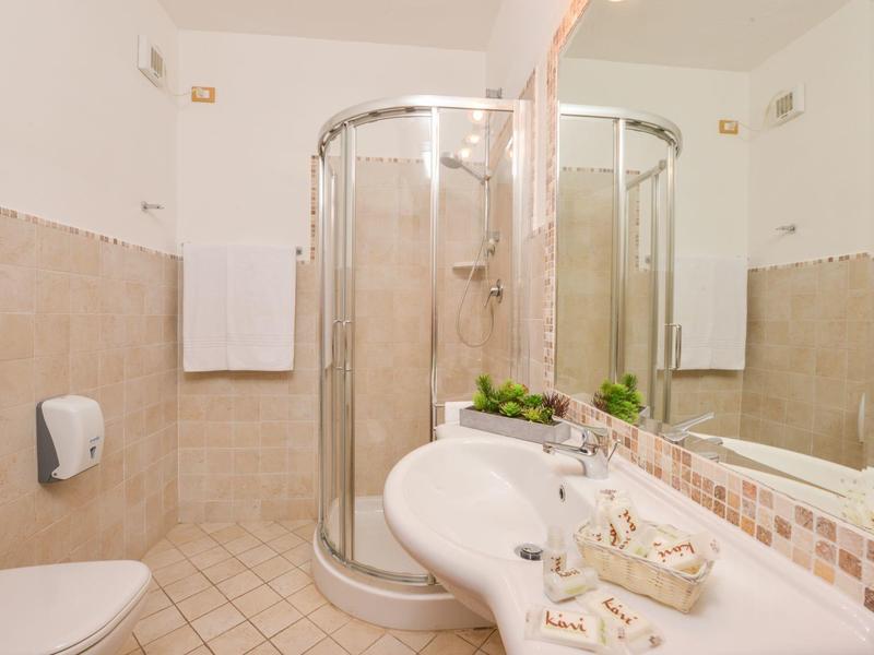 Bagno moderno con doccia rotonda, lavabo e WC in colori neutri.