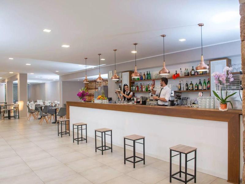 Area bar dell'hotel moderna con bancone, sgabelli e barista dietro il bancone.