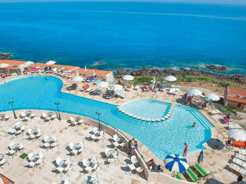 Grande piscina dell'hotel con lettini e vista sul mare.