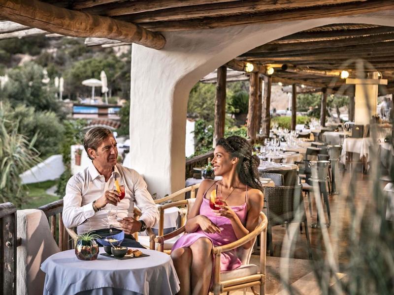 Una coppia gusta bevande su una terrazza coperta con vista su colline verdi.