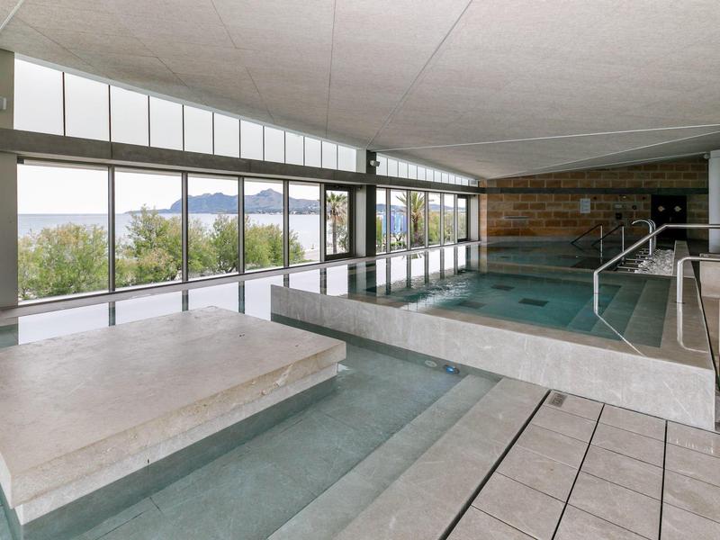 Área de piscina interior con ventanales y vista a árboles, moderno y limpio.