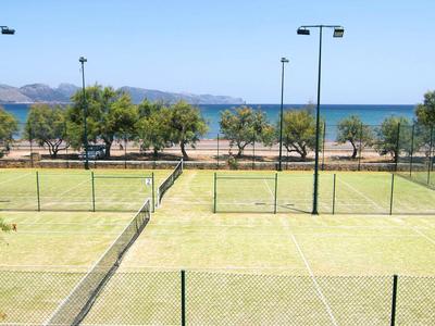 Zwei Tennisplätze mit Blick auf das Meer und Bäume im Hintergrund.