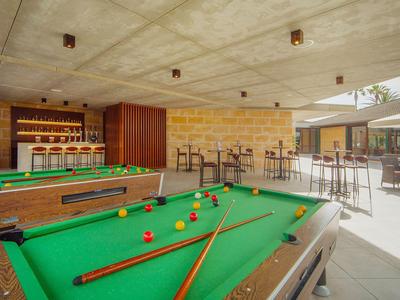Bright lounge area with two pool tables and seating in a modern hotel setting.