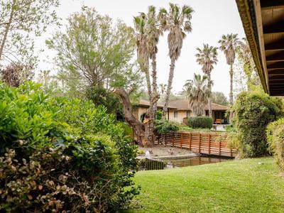 Gegroei tuin met palmbomen, groen en een houten hek naast een hotelgebouw.