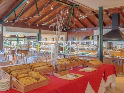 Hotelontbijtbuffet met gebak en brood in een ruime eetzaal met houten plafond.
