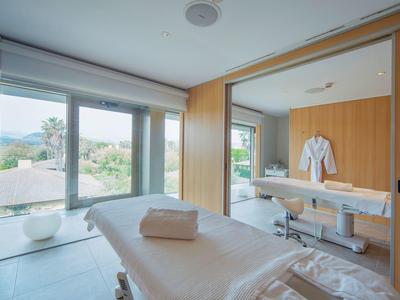 Salle de bien-être moderne avec table de massage et grande fenêtre avec vue.
