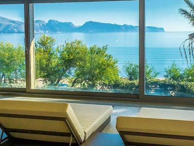 Espace lounge avec chaises longues et vue sur la mer derrière de grandes fenêtres