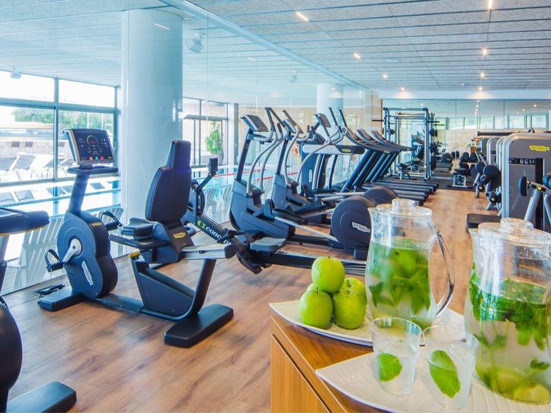 Salle de sport moderne avec vélos stationnaires, tapis de course et boissons rafraîchissantes.