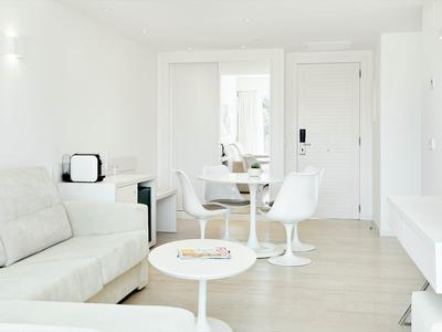 Jasny salon z białą sofą, okrągłymi stolikami i nowoczesną jadalnią