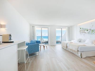 Helles, modern eingerichtetes Hotelzimmer mit Doppelbett, Balkon und Meerblick.