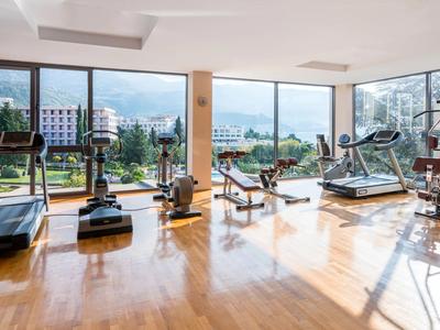 Moderner Fitnessraum mit großem Fenster und Sportgeräten mit Blick auf Stadt und Berge.