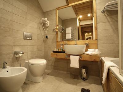 Modernes Hotelbad mit Waschbecken, Toilette, Bidet und Spiegel in warmen, beigen Tönen