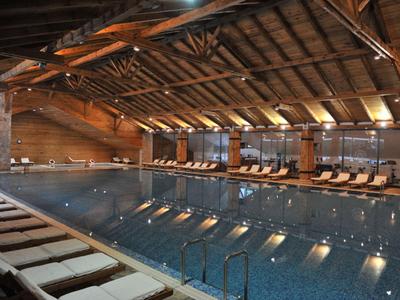 Innenpool mit Holzdecke und Liegestühlen entlang der Seite in einem Hotel.