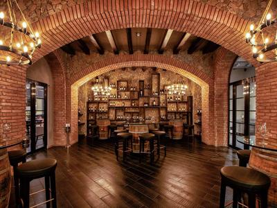 Gemütlicher Raum mit roten Backsteinbögen, Holzdecke, dunklem Holzboden und Kronleuchtern.