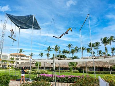Person springt auf einem Trampolin mit Sicherheitsnetz in einem tropischen Resort.