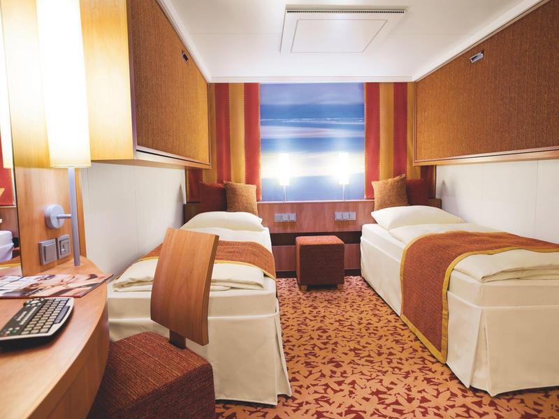 Zwei Einzelbetten mit weißen Bettlaken und braunen Decken in gemütlichem Hotelzimmer mit Teppichboden.