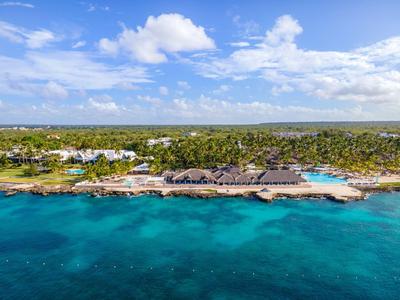 Blick auf tropisches Resort am Meer mit klarem, türkisblauem Wasser und bewölktem Himmel.